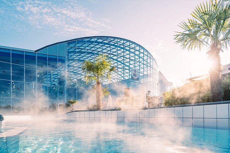 A Pool With A Building And Palm Trees