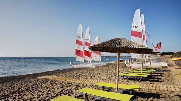 A Beach With Chairs And Umbrellas And Boats