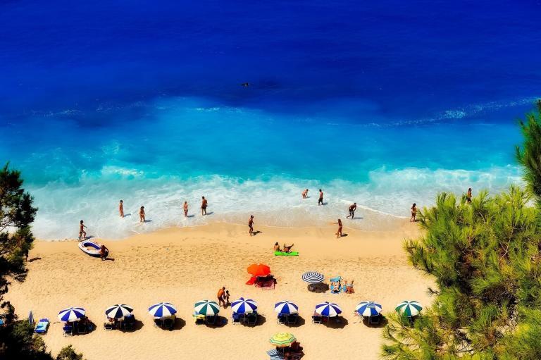 A Group Of People On A Beach With Umbrellas And Chairs