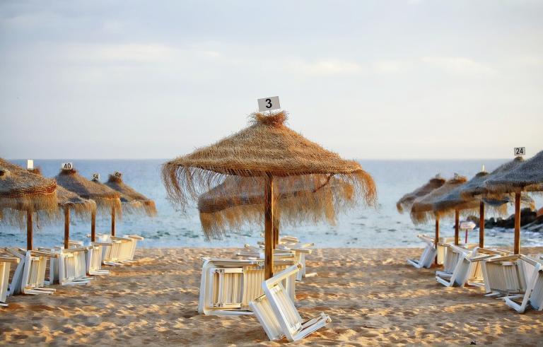 A Beach With Umbrellas And Chairs