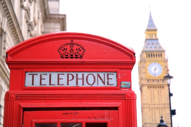 A Red Telephone Booth With A Clock Tower In The Background