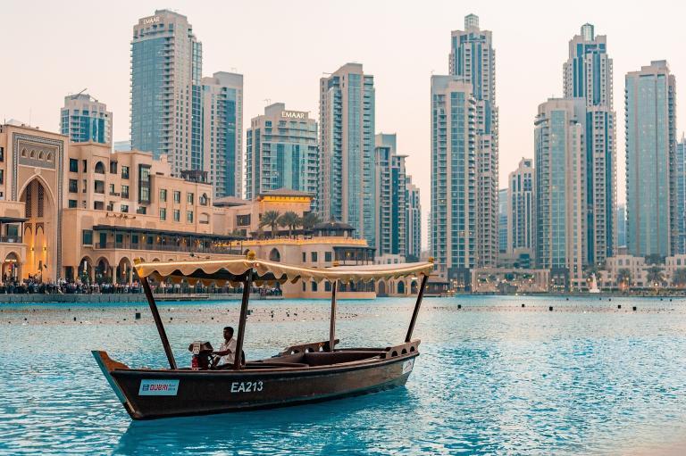 A Boat In The Water With A City In The Background