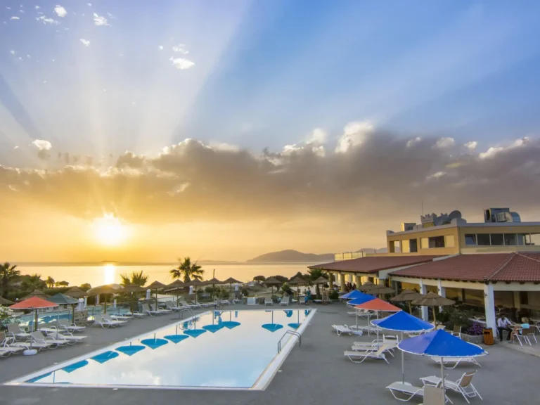 A Pool With Umbrellas And Chairs By Buildings And Water