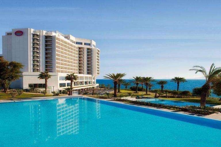 A Large Pool With Palm Trees And A Building With A Body Of Water