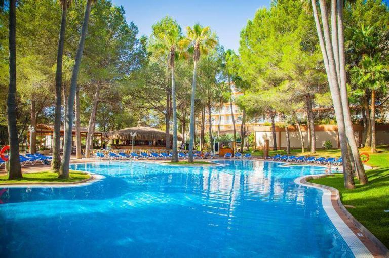 A Pool With Chairs And Trees Around It