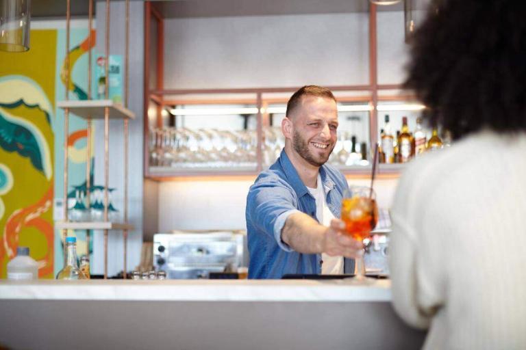 A Man Handing A Drink To Another Man