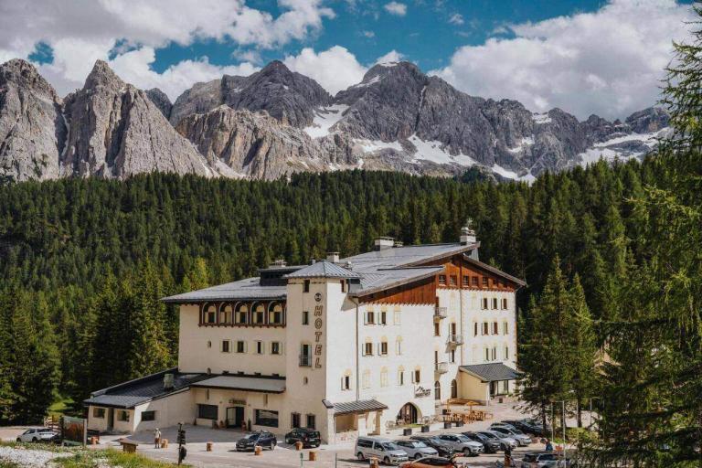 A Building With Cars Parked In Front Of Mountains