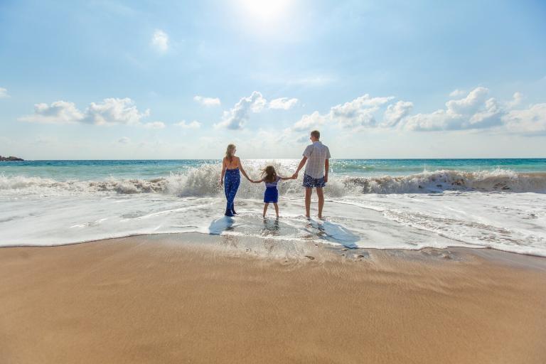 A Man And Woman Holding Hands And Standing On A Beach