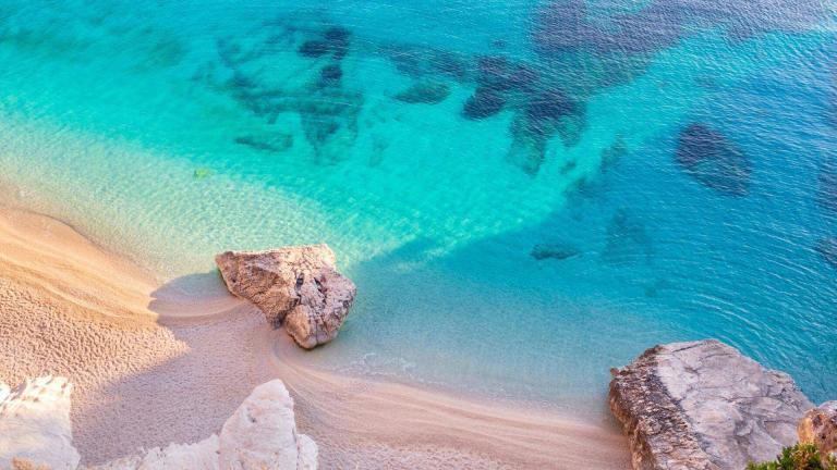 A Beach With Rocks And Clear Blue Water