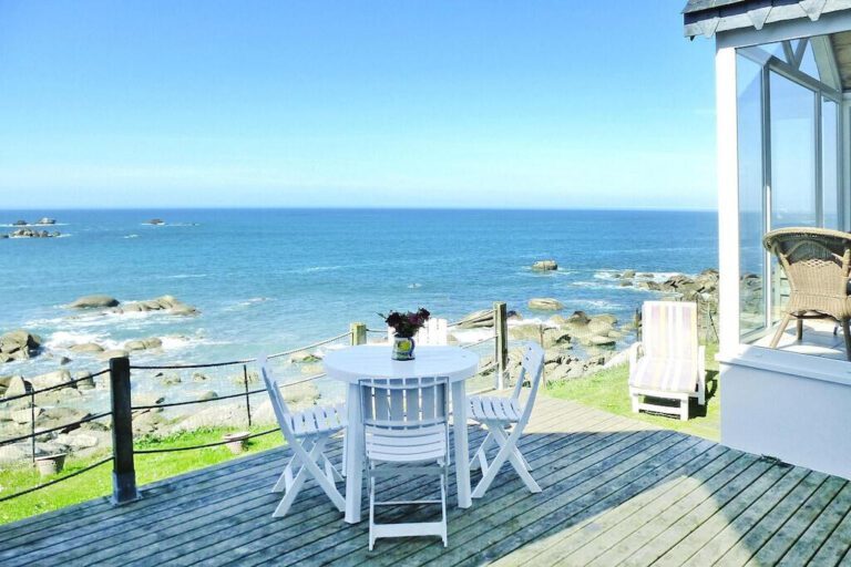 A Table And Chairs On A Deck Overlooking The Ocean