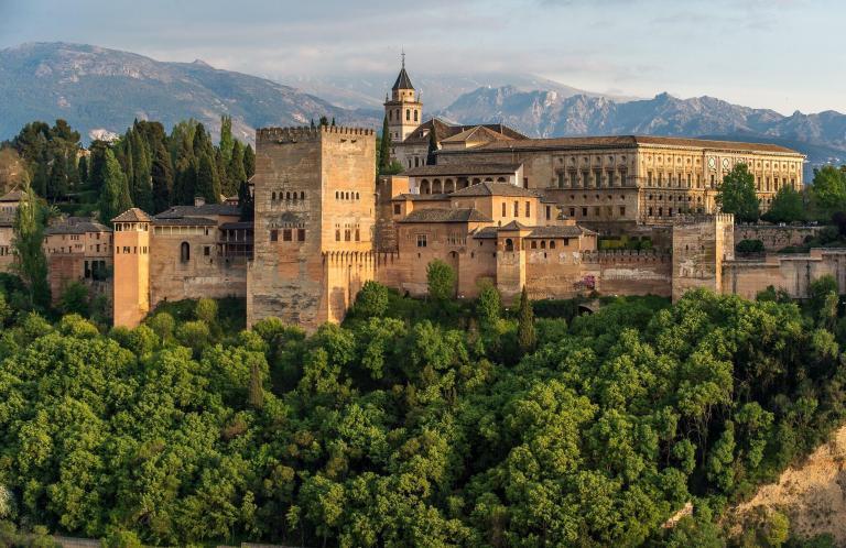 A Large Stone Building With Trees In The Background With Alhambra In The Background